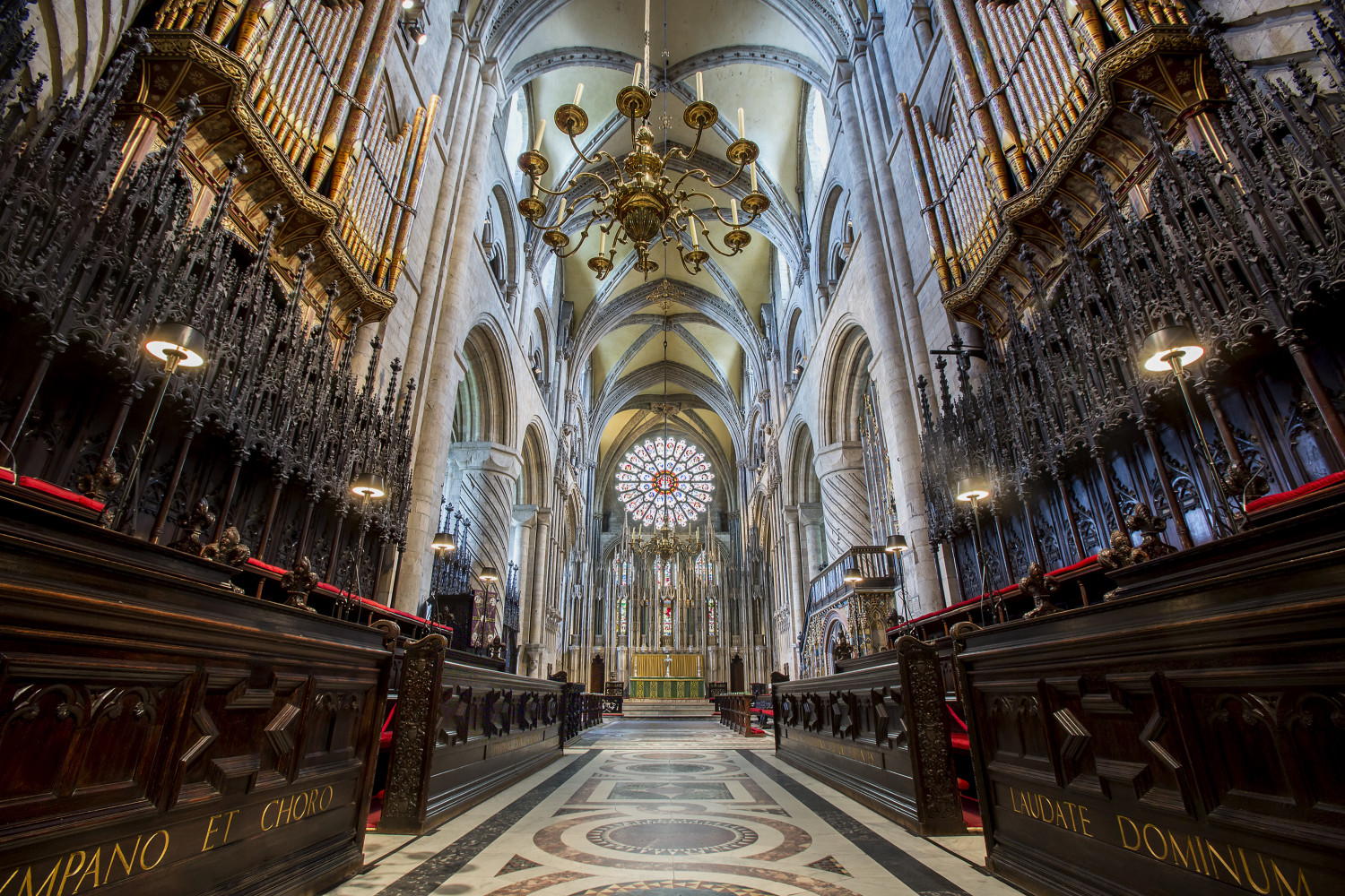 View of the Cathedral Quire showing the seats running parallel to the aisle, the altar, and the stained glass window.